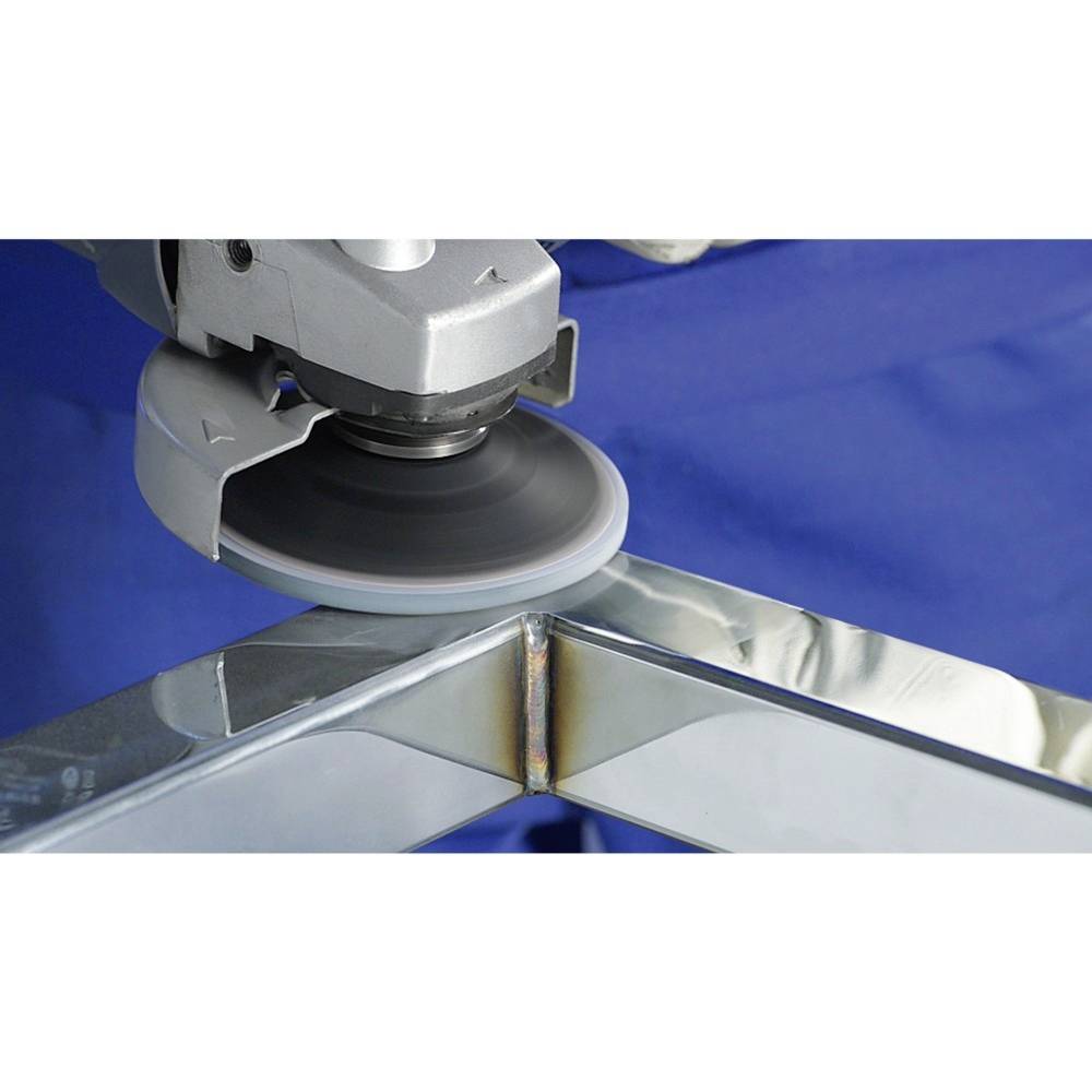 Eine Schleifmaschine bearbeitet eine Metallecke. Die Funken zeigen, dass das Werkzeug im Einsatz ist. Die Maschine ist silberfarben.