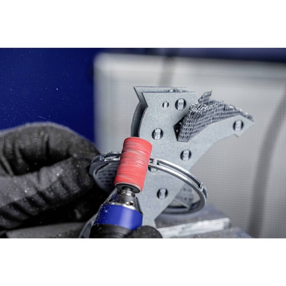 Eine Person schleift ein 3D-gedrucktes Metallteil mit einer rotierenden Schleifmaschine.