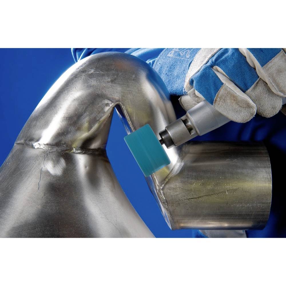 Person schleift ein Metallrohr mit einer Maschine, trägt blaue Arbeitshandschuhe. Fokus auf die handwerkliche Arbeit.