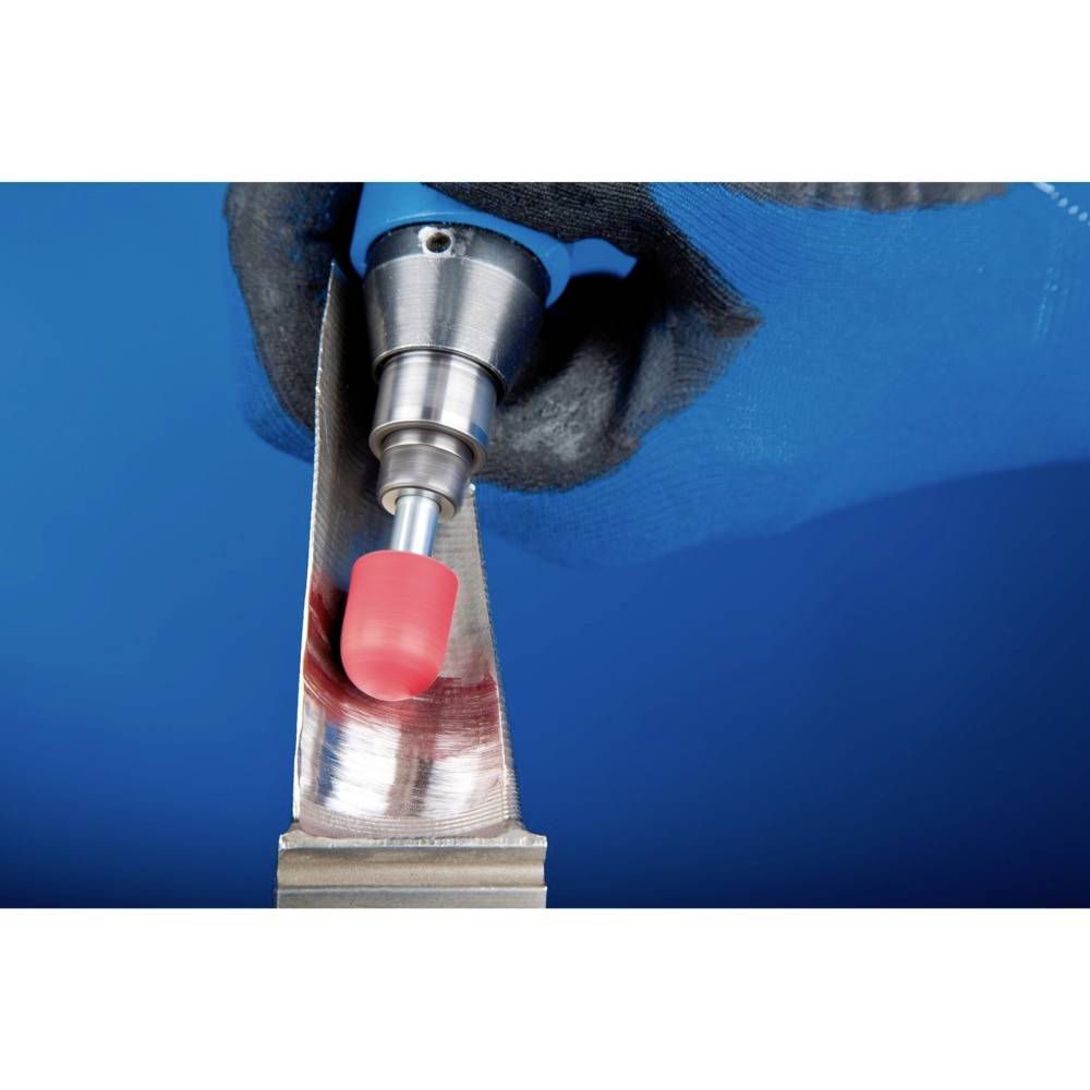 Eine Person schleift die Kante eines Metallstücks mit einem rotierenden Werkzeug mit rotem Schleifkopf. Handschuhe schützen die Hände.
