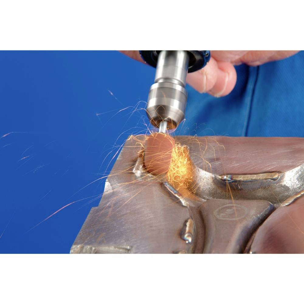 Eine Hand schleift Metall mit einer rotierenden Werkzeugmaschine, Funken fliegen. Hintergrund in kräftigem Blau.