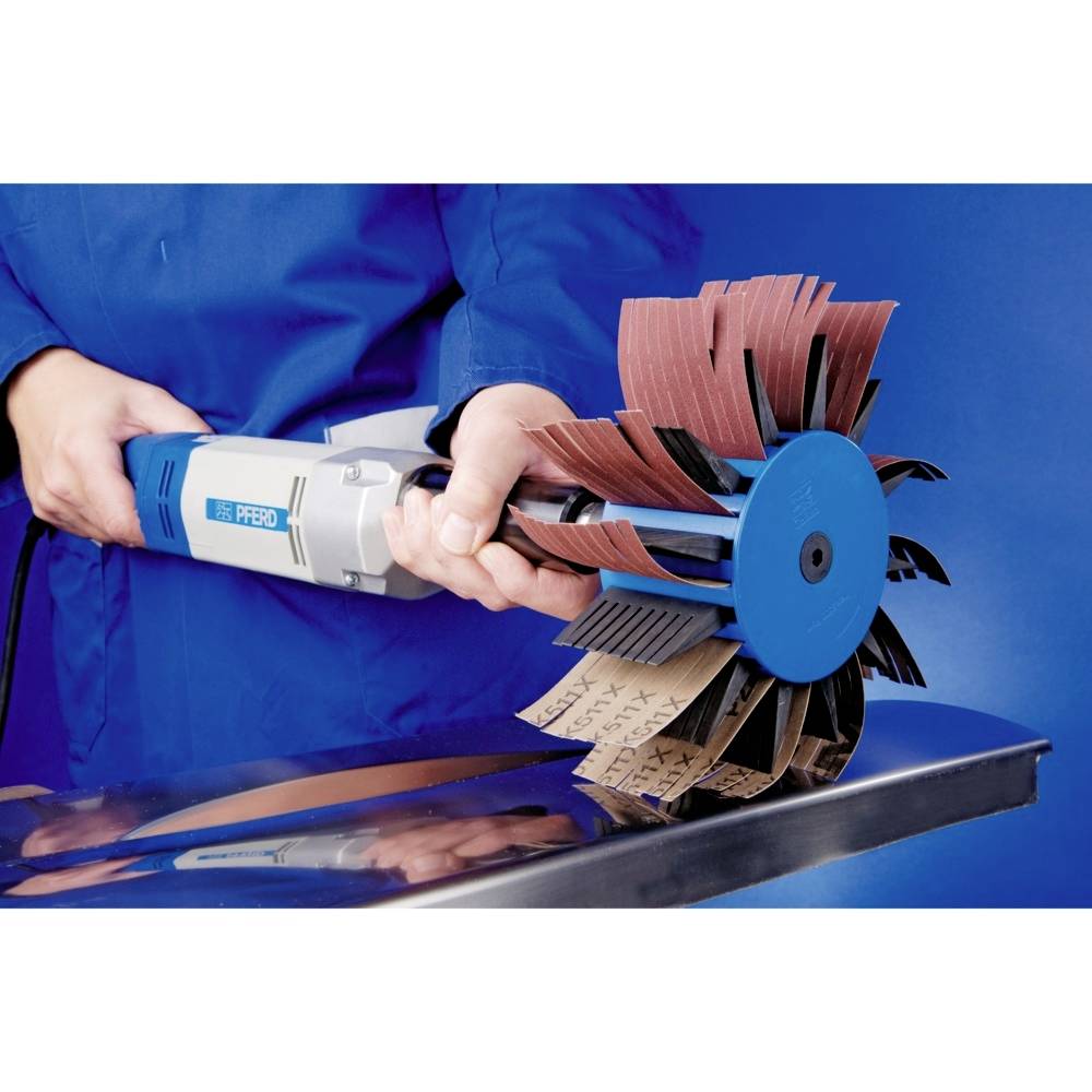 Ein Gerät mit großer Schleifbürste wird von einer Person in blauer Kleidung gehalten. Es wird auf einer Metallfläche verwendet.