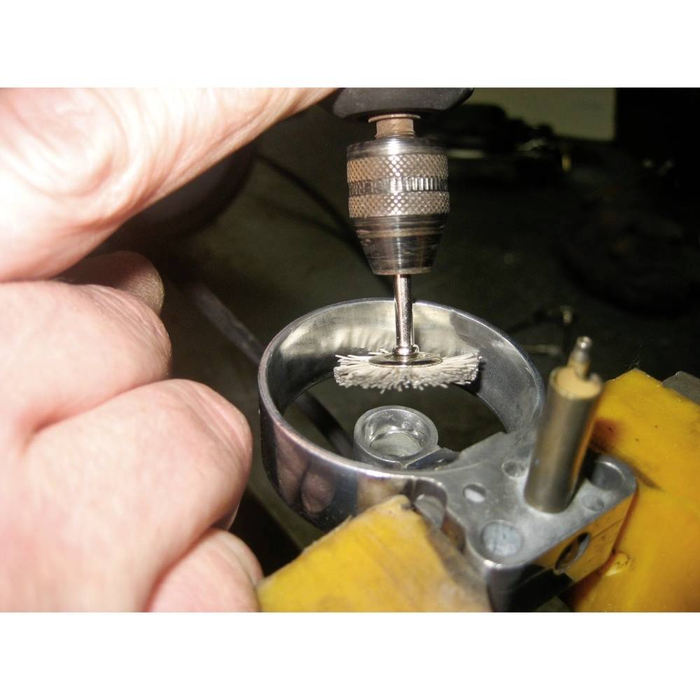 Ein Hand hält ein rotierendes Werkzeug, das Metall in einem Werkstattsetting poliert oder schleift.