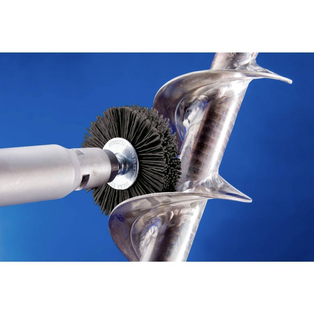 Eine Metallbürste reinigt die glatte Oberfläche einer großen Metallschnecke vor einem blauen Hintergrund.