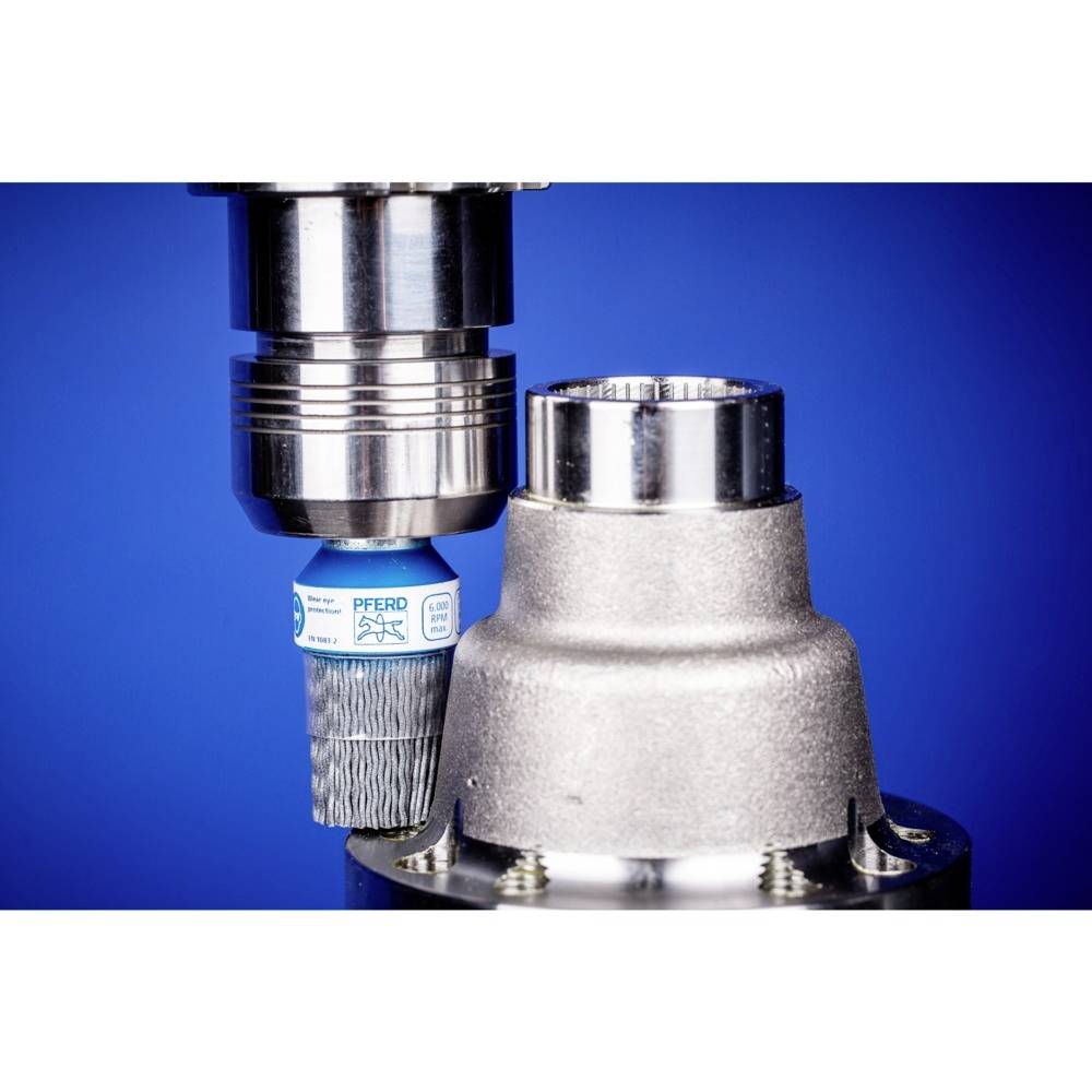 Eine Metallbürste wird in einer Montagemaschine präzise eingesetzt, vor einem Hintergrund in kräftigem Blau.