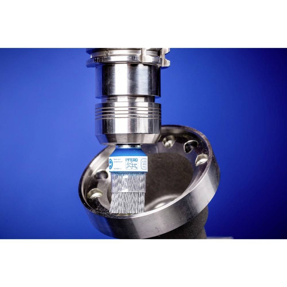 Eine Metallbürste bearbeitet eine runde Metallfläche, umgeben von einem blauen Hintergrund.