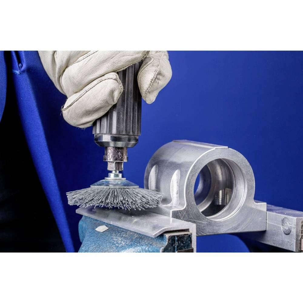 Hand poliert Metalloberfläche mit rotierendem Werkzeugbürste, blauer Hintergrund.