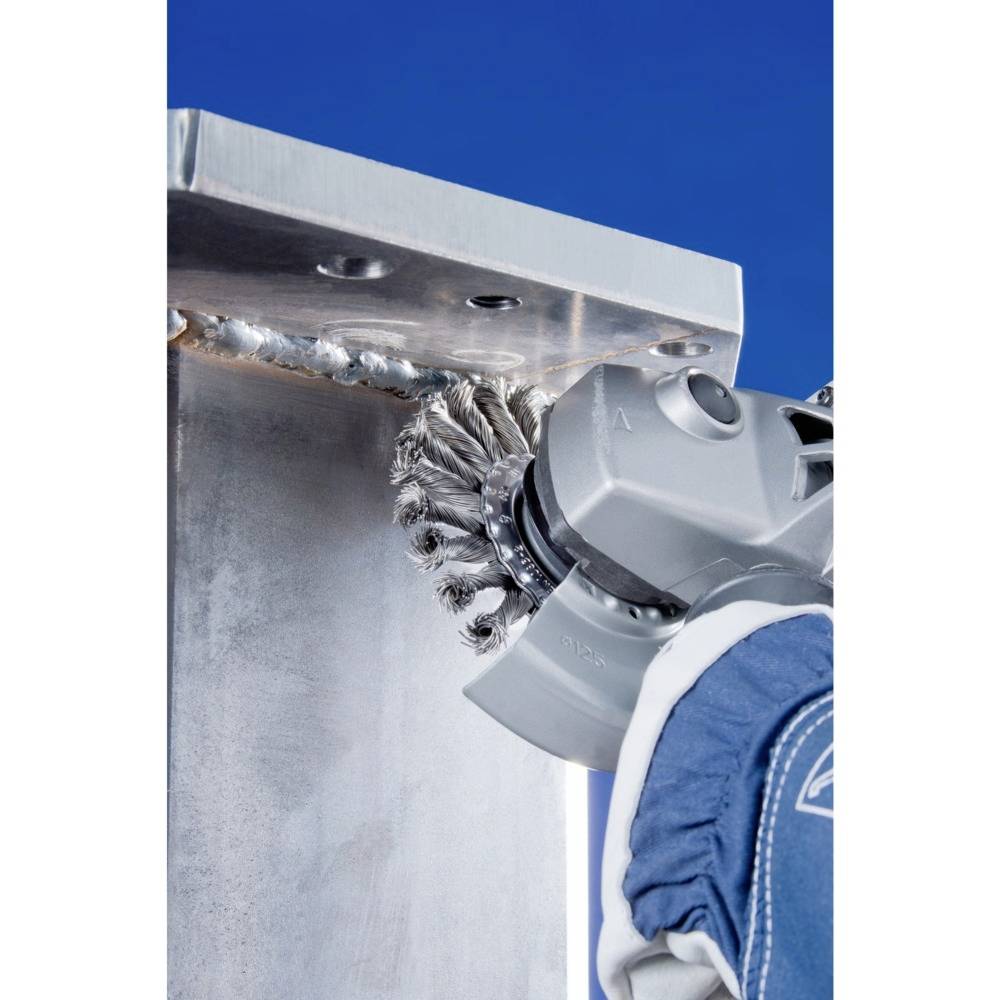 Ein Roboterarm führt eine metallene Bürste über eine geschweißte Metallnaht, um sie zu reinigen. Die Umgebung ist industriell.