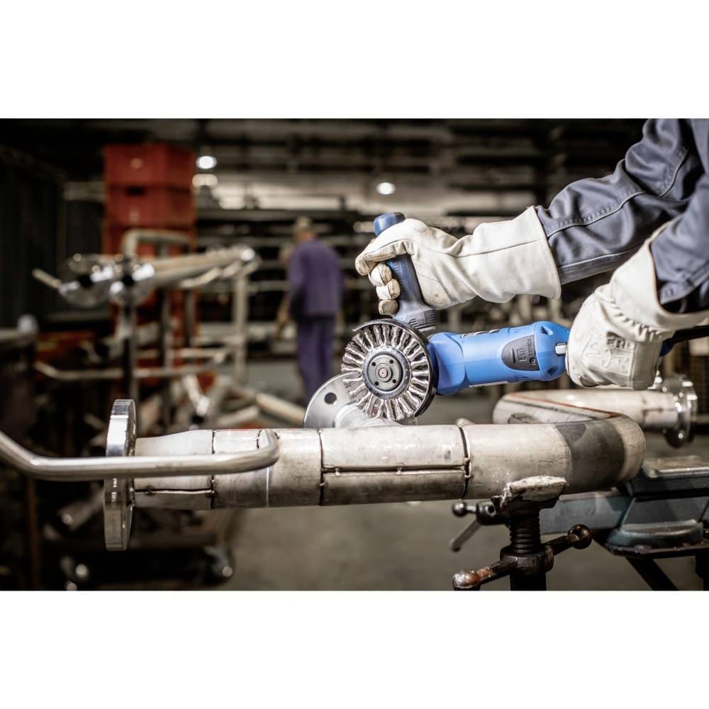 Arbeiter in Sicherheitsausrüstung verwendet Schleifmaschine auf Metallrohr in Werkstatt.