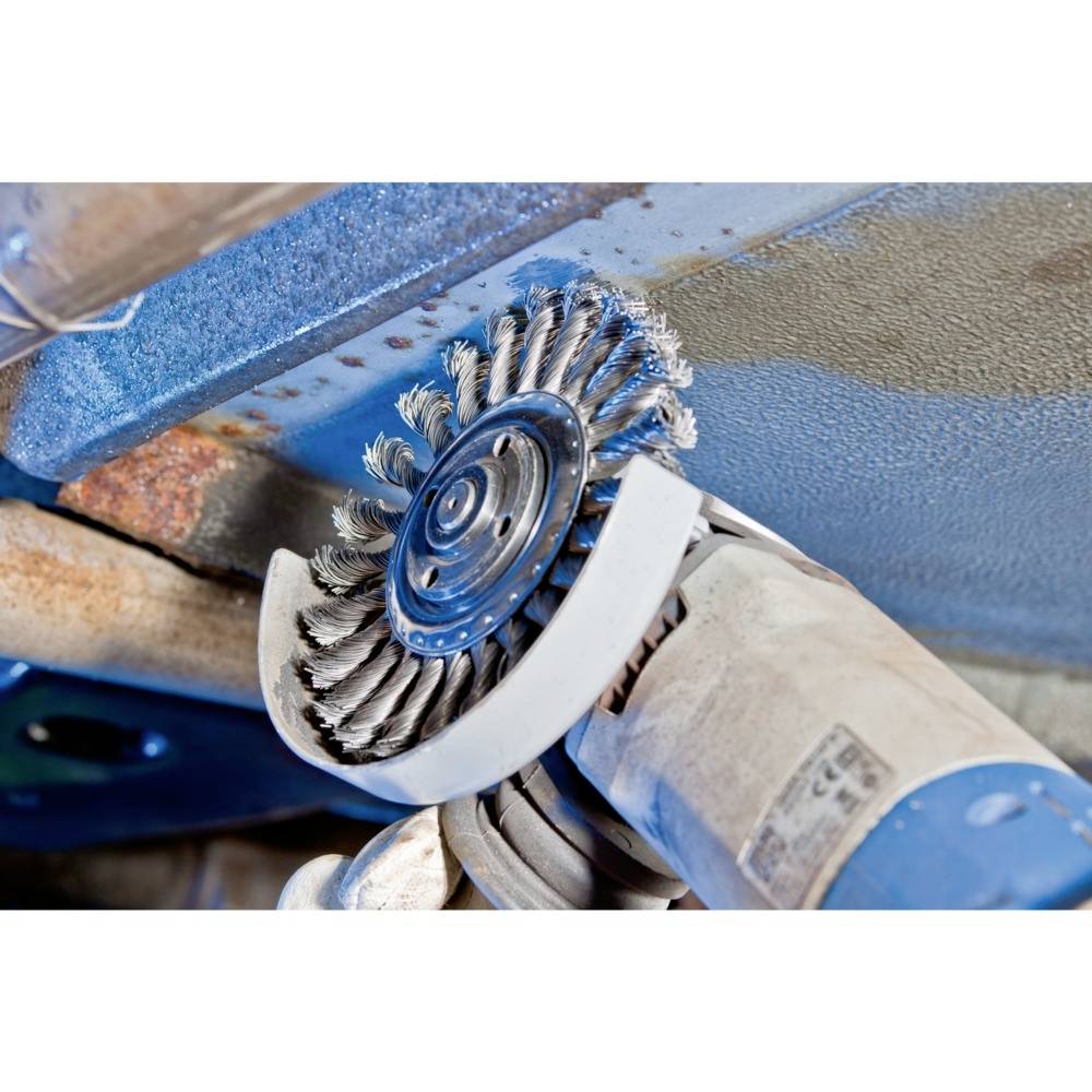 Ein blauer Winkelschleifer mit Drahtbürstenaufsatz bearbeitet eine Metalloberfläche, entfernt Rost und bereitet sie für die Lackierung vor.