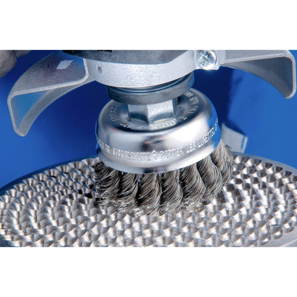 Runde Stahlbürste reinigt eine metallische Oberfläche. Die Borsten der Bürste bewegen sich über die Oberfläche mit gleichmäßigem Druck.