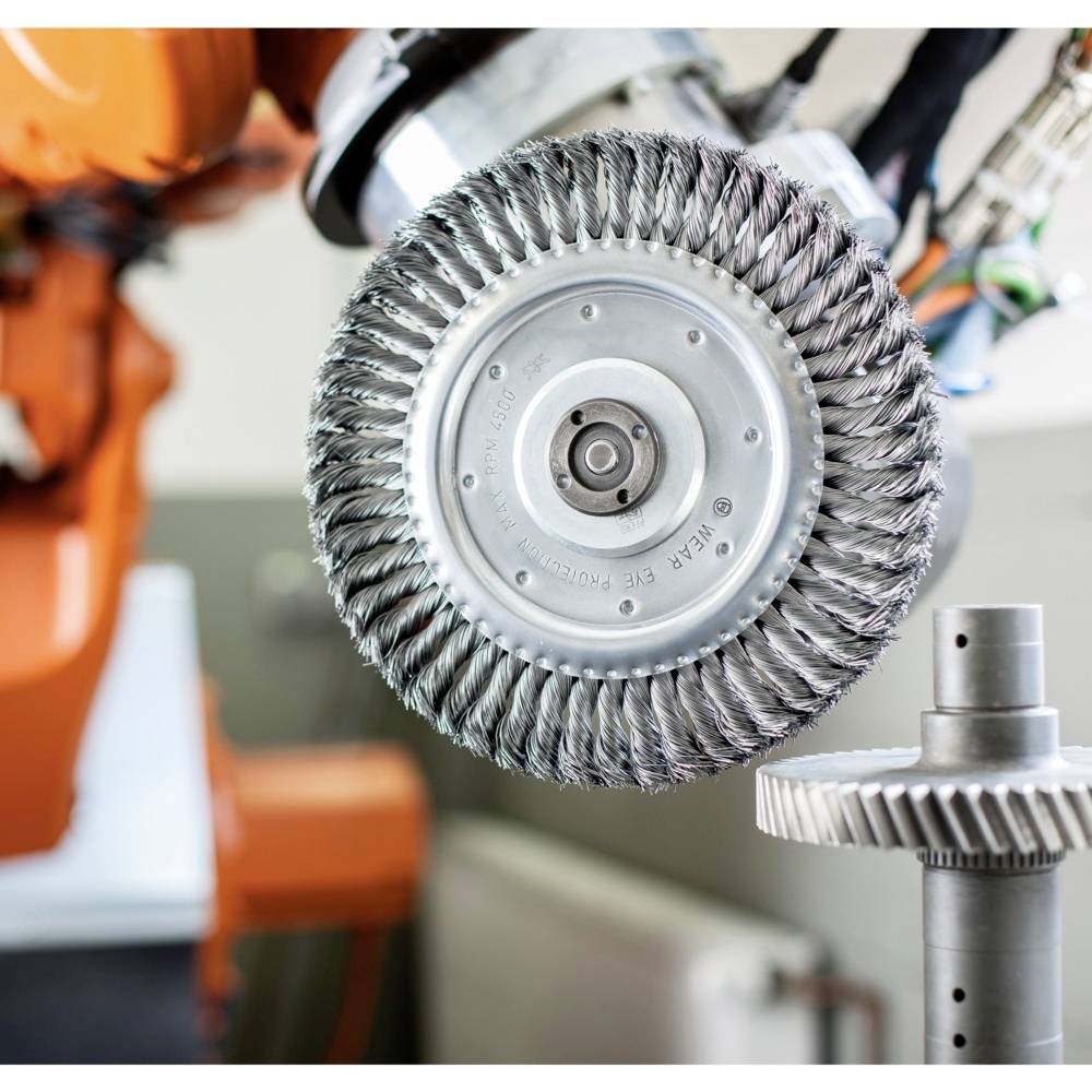 Industrieroboter mit rotierenden Bürsten entfernt Material von einem metallischen Zahnrad, um es zu polieren oder zu glätten.