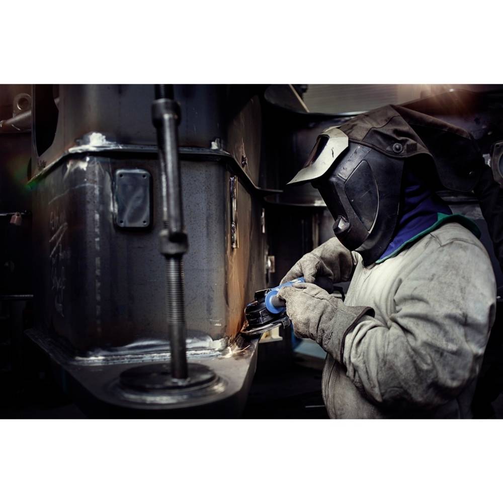 Arbeiter in Schutzkleidung schweißt Metall in einer industriellen Umgebung.