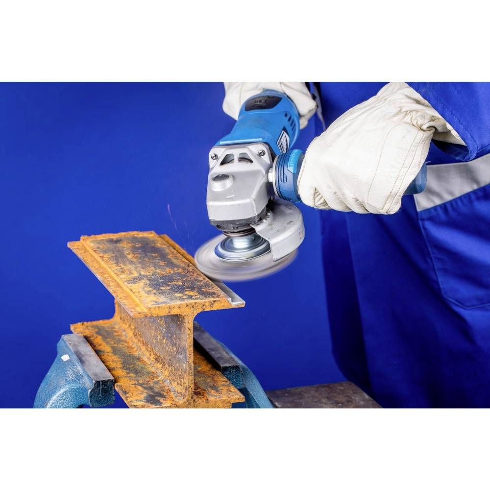 Eine Person mit blauen Handschuhen schleift mit einer Winkelschleifmaschine Rost von einem Metallstück.