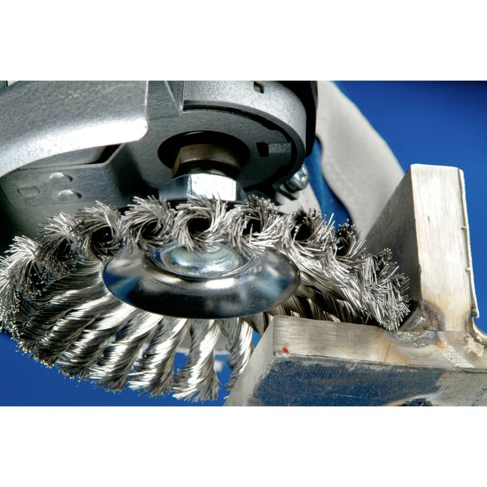 Eine rotierende Drahtbürste bearbeitet die Oberfläche eines Metallteils. Das Werkzeug entfernt Material, um eine glatte Oberfläche zu schaffen.