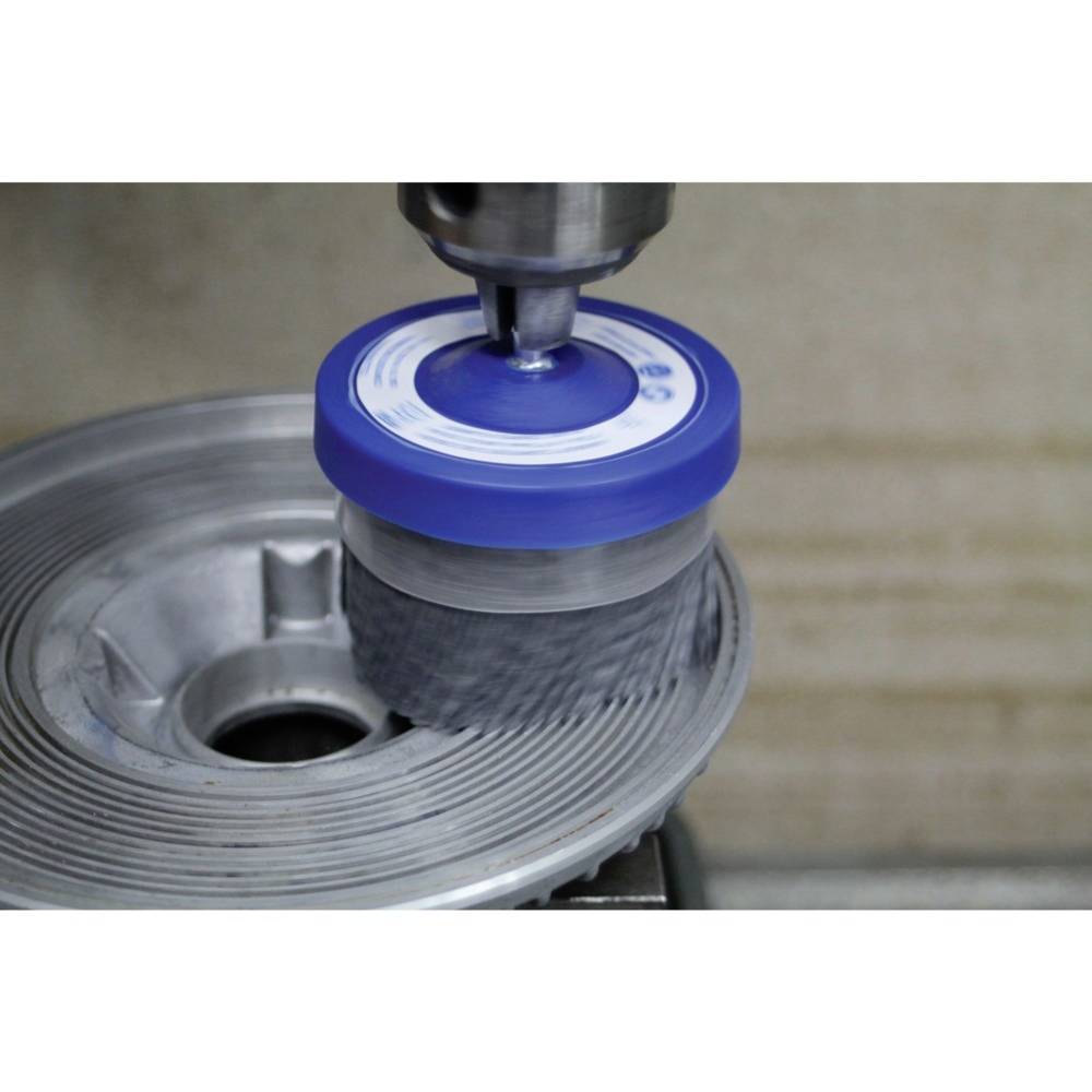 Eine rotierende Drahtbürste reinigt eine metallische Oberfläche, wobei Schmutz und Rost entfernt werden. Fokus auf die Mechanik des Prozesses.