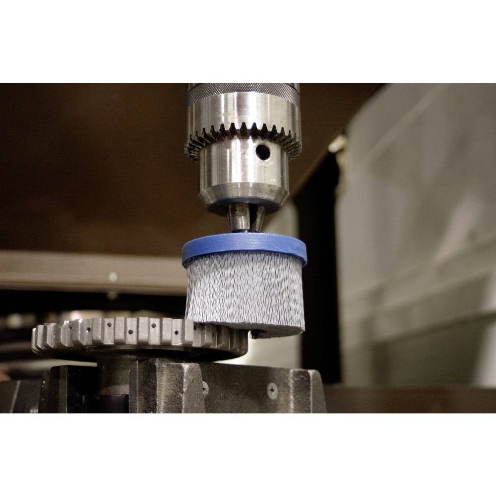 Eine rotierende technische Bürste bearbeitet ein Metallzahnrad. Die Szene zeigt einen industriellen Bearbeitungsprozess.