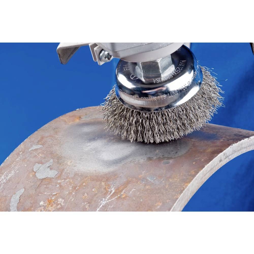 Ein Handwerkzeug mit Runddrahtbürste reinigt eine rostige Metalloberfläche auf blauem Hintergrund.