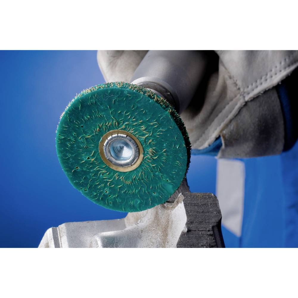 Ein grüner Schleifaufsatz an einem Winkelschleifer wird verwendet, um Metall zu bearbeiten. Ein Handschuh hält den Griff fest.