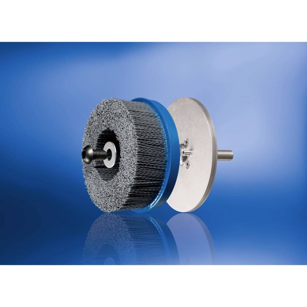 Eine runde Drahtbürste auf einer Spindel, vor einem blauen Hintergrund. Sie wird für die Oberflächenbearbeitung eingesetzt.