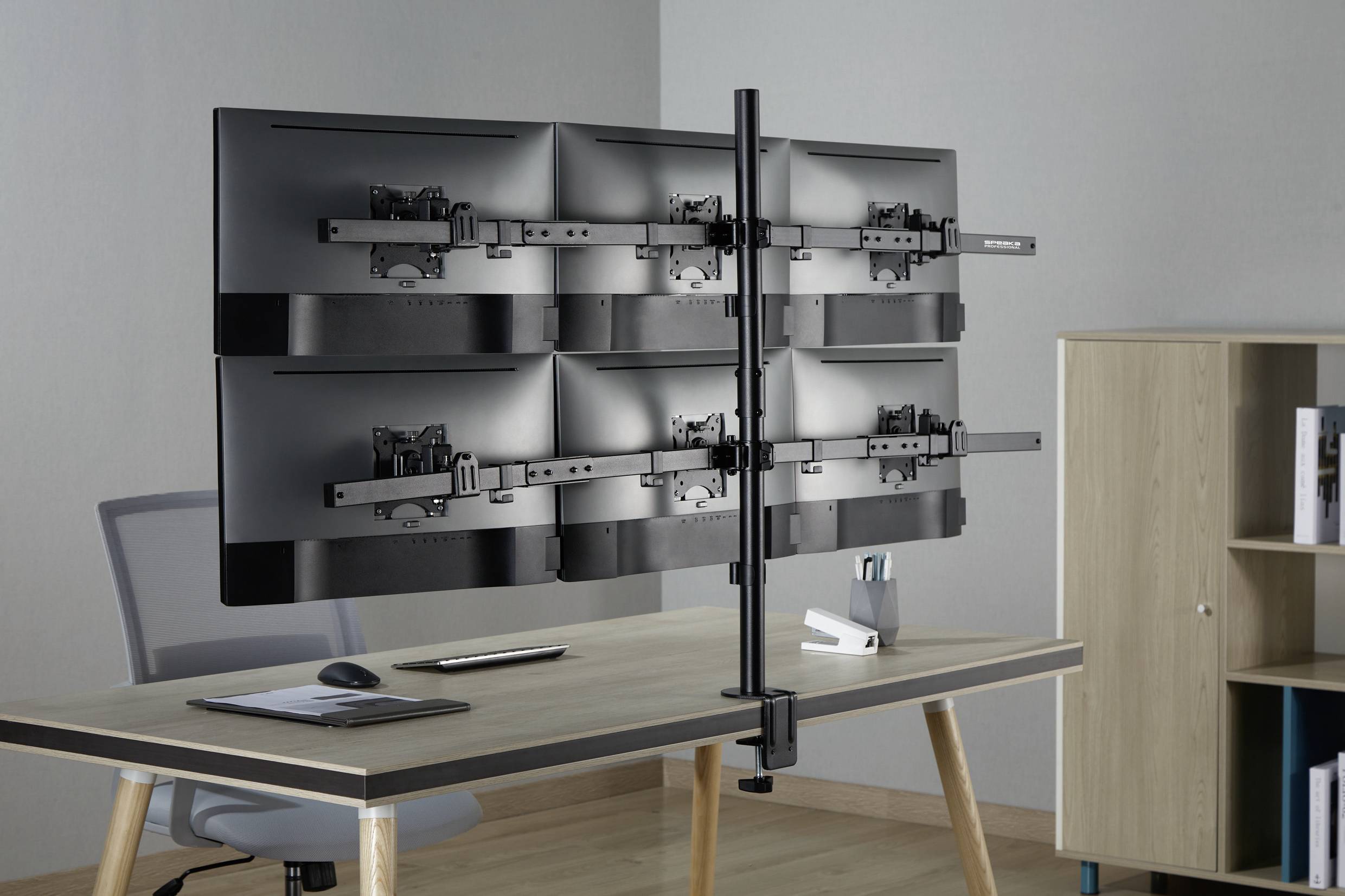 Eine Schreibtischklemme hält sechs Monitorhalterungen, die an zwei übereinander gestapelten Reihen befestigt sind, auf einem Schreibtisch in einem Büro.