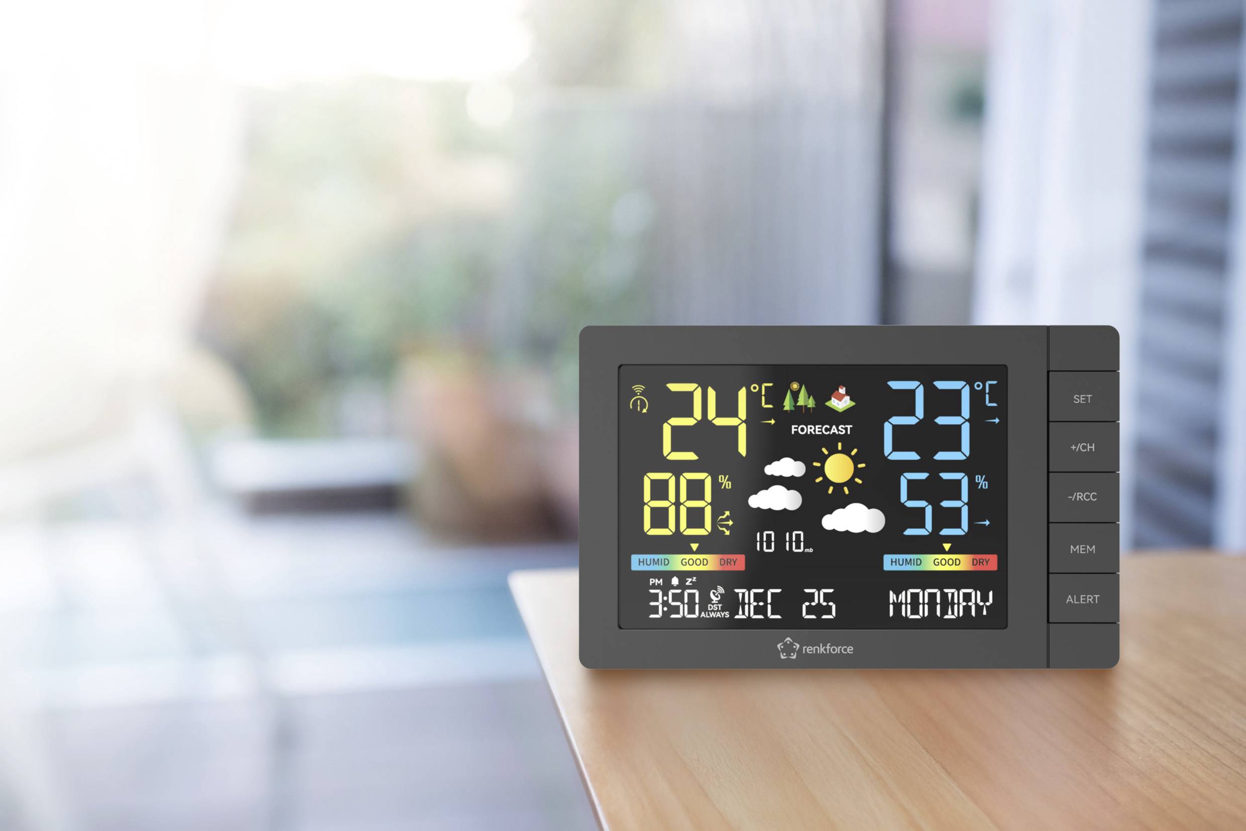 Ein digitaler Wetterstation-Bildschirm zeigt Temperaturen: innen 24°C, außen 23°C. Luftfeuchtigkeit: innen 88%, außen 53%. Prognose: Sonne und Wolken, Montag.