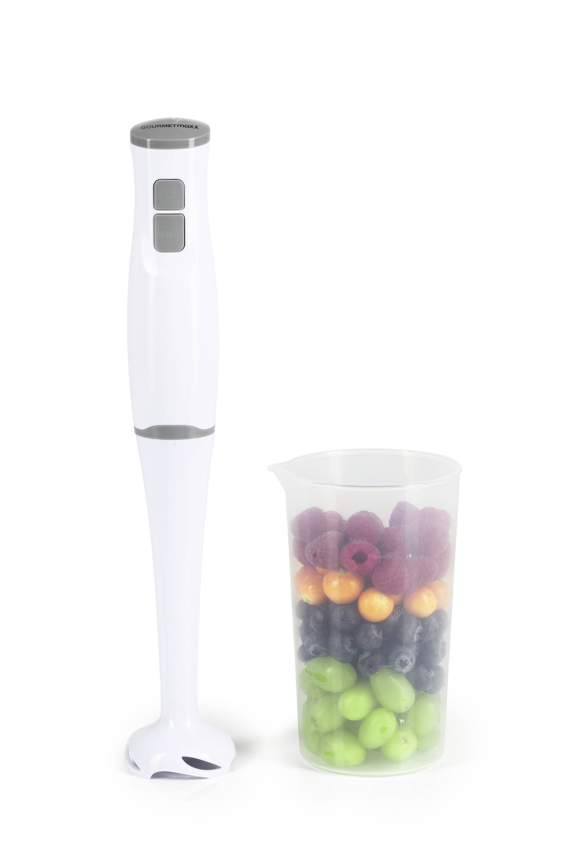 Ein weißer Stabmixer steht neben einem durchsichtigen Behälter, der mit farbigen Früchten wie grünen Äpfeln, Trauben und Himbeeren gefüllt ist.