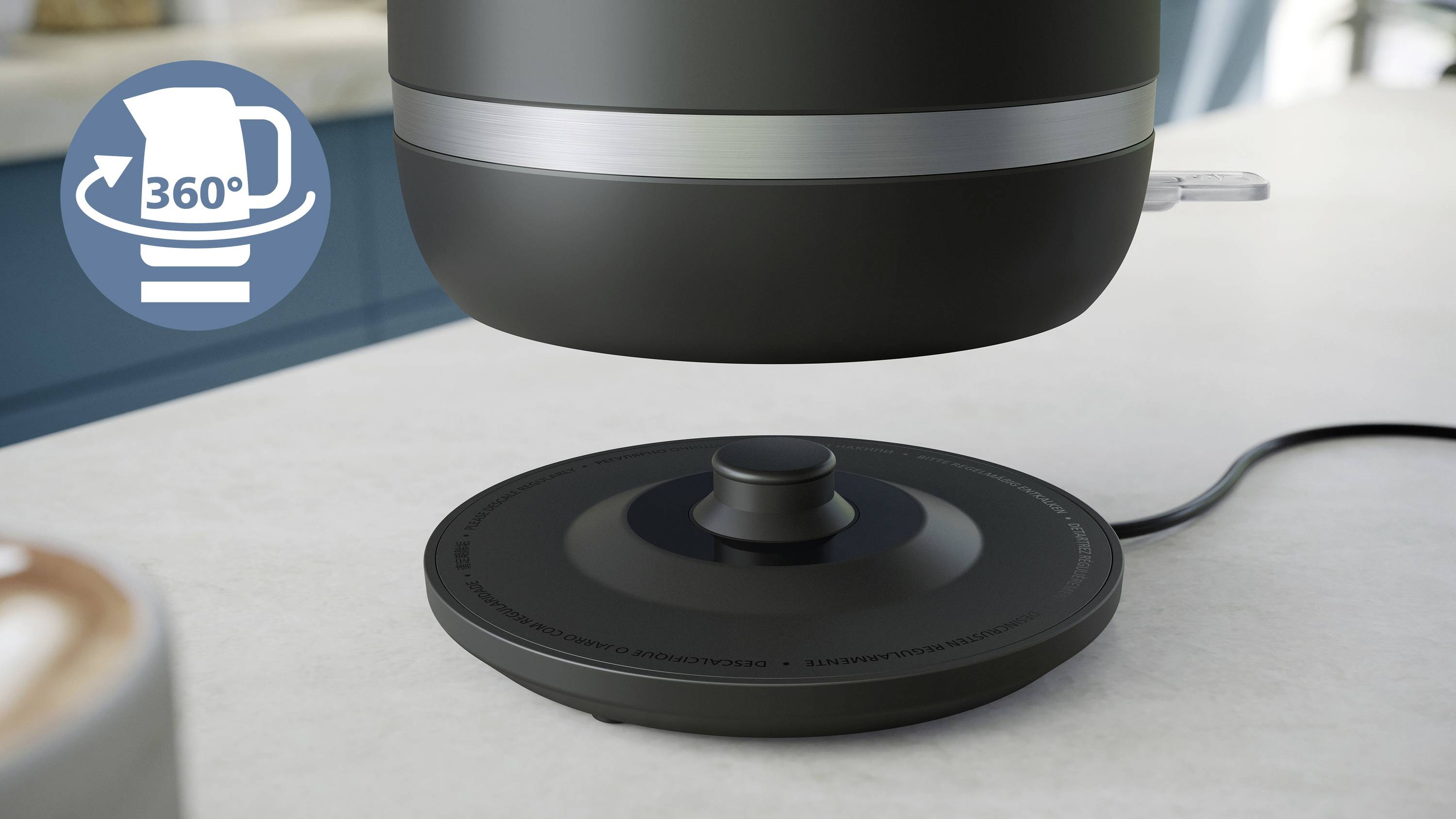 Ein Wasserkocher wird über seiner Basis gehalten, mit einem Symbol für '360°' Rotation; im Hintergrund verschwommen eine Küche.