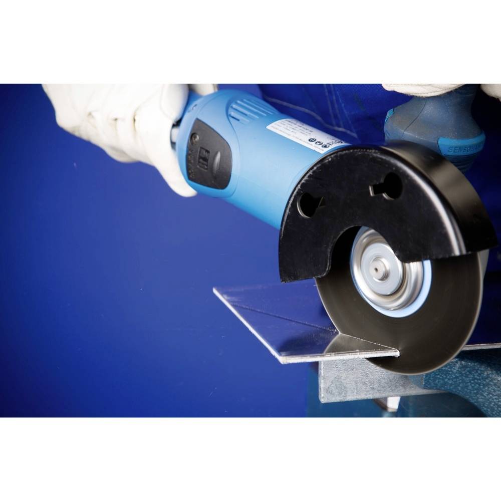 Arbeiter nutzt eine blaue Winkelschleifmaschine zum Schneiden eines Metallstücks. Der Hintergrund ist blau, Arbeitsschutzkleidung wird getragen.