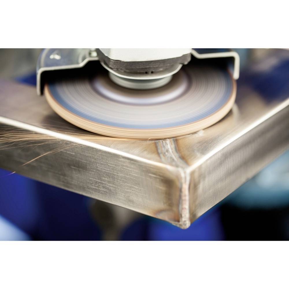Eine Schleifmaschine bearbeitet eine Metallkante, erzeugt Funken. Die Szene zeigt handwerkliches Arbeiten mit Fokus auf den Schleifvorgang.