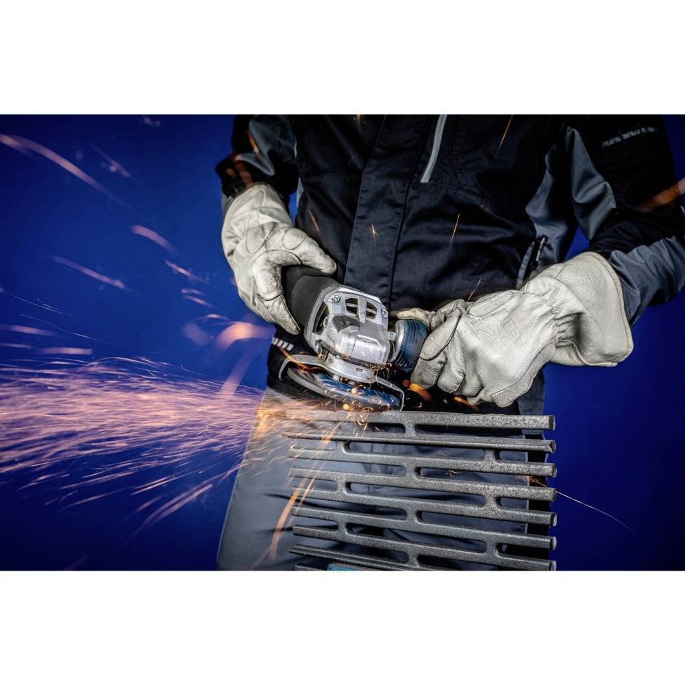 Person schleift Metall mit einer Schleifmaschine. Funken sprühen, Person trägt Handschuhe. Hintergrund ist blau.