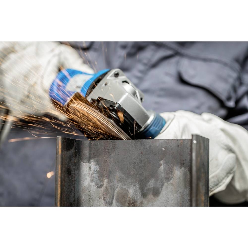 Eine Person schleift mit einem Winkelschleifer Metall. Funken sprühen. Die Person trägt Sicherheitskleidung und Handschuhe.