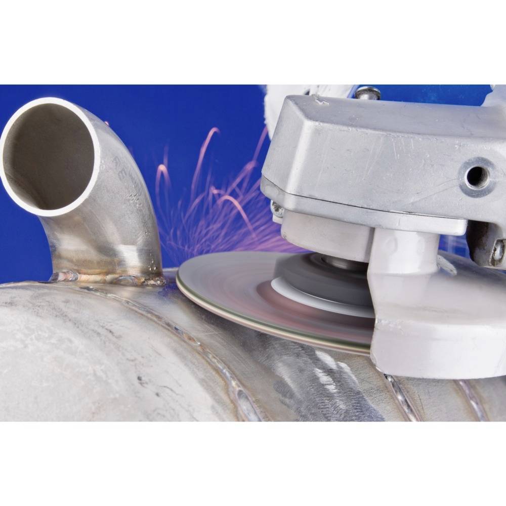 Eine Schleifmaschine bearbeitet die Oberfläche eines Metallrohrs, während im Hintergrund Funken sprühen.