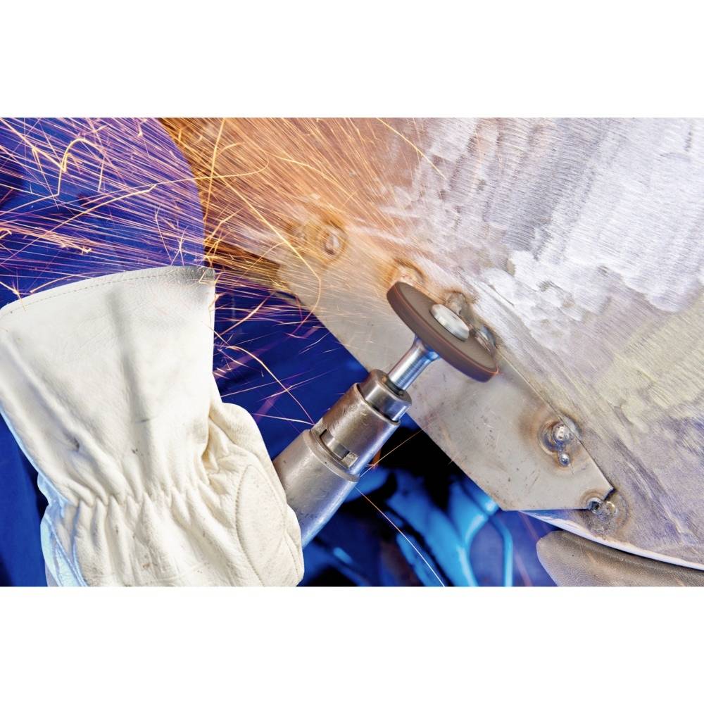 Funken sprühen von einem Winkelschleifer, der an einem Metallstück arbeitet. Ein Arbeiter trägt Arbeitshandschuhe zum Schutz.