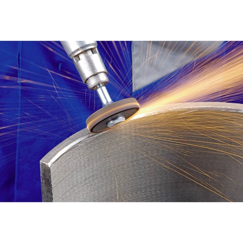 Eine Maschine schleift einen Metallzylinder, wobei Funken sprühen. Blaue Schutzausrüstung im Hintergrund.