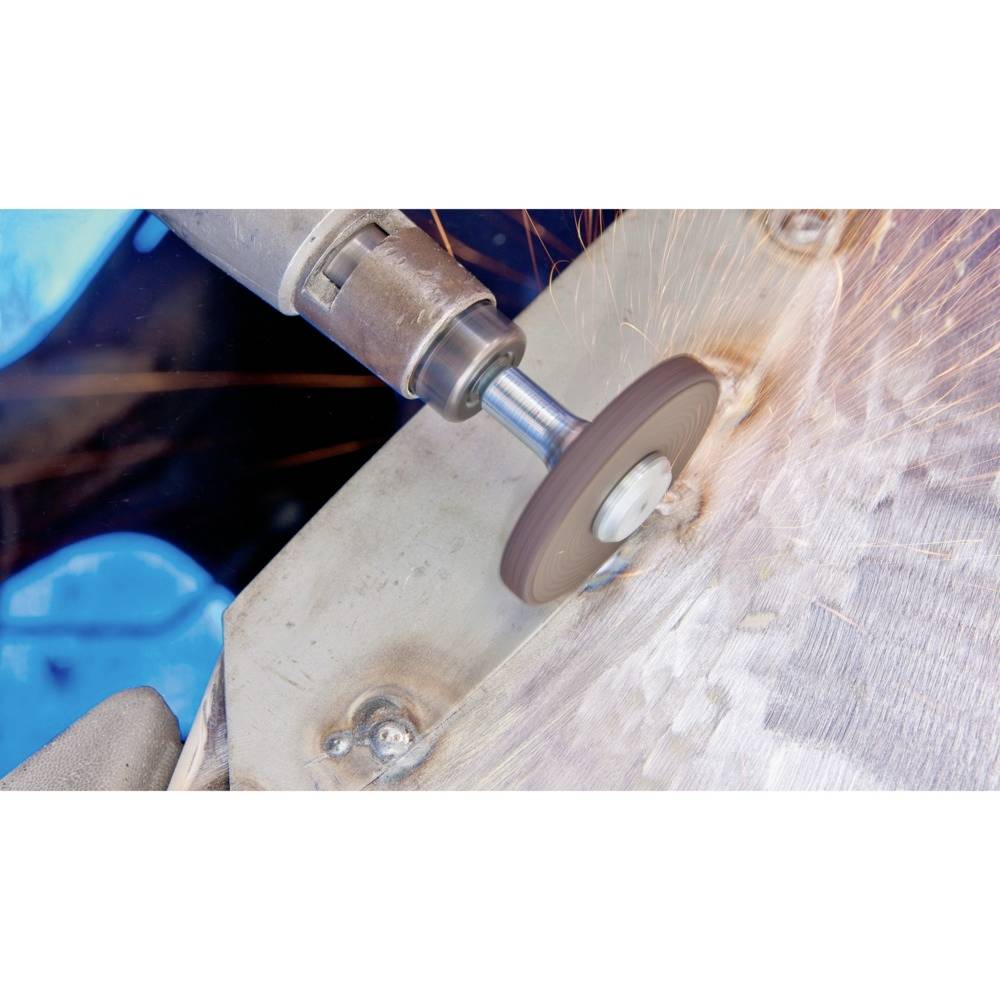 Eine Schleifmaschine bearbeitet eine Metalloberfläche, Funken fliegen. Hauptvorgang ist das Schleifen oder Polieren von Metall.