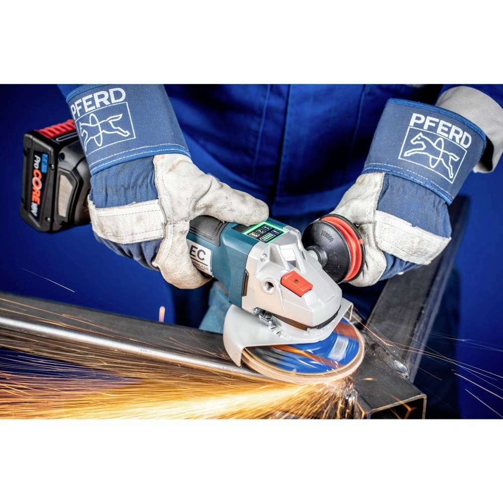 Arbeiter verwendet Winkelschleifer, Funken fliegen. Schutzhandschuhe und Schutzkleidung tragen. Metalbearbeitung in Werkstattumgebung.