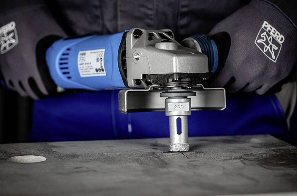 Eine Person verwendet eine blaue Maschine mit einem rotierenden Werkzeugaufsatz, um eine Metallplatte zu bearbeiten.