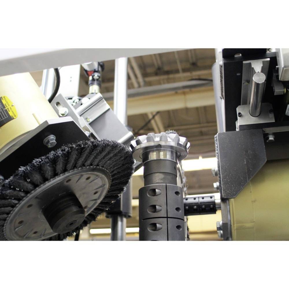 Ein industrielles Schleif- und Polierwerkzeug bearbeitet ein metallisches Zahnrad in einer Fabrikumgebung.