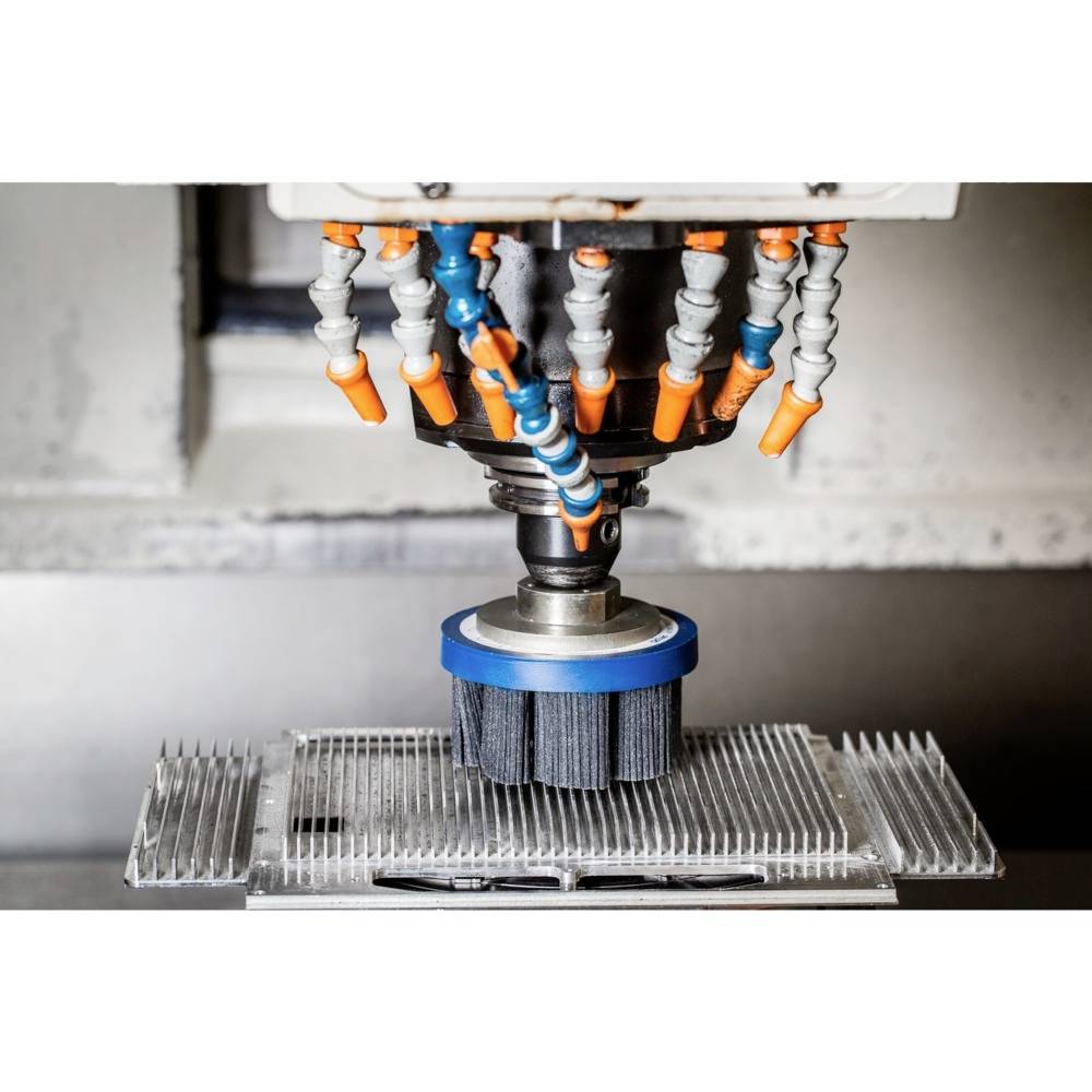 Eine CNC-Maschine mit rotierenden Bürsten reinigt parallel angeordnete Aluminiumlamellen, um präzise Oberflächenbearbeitung zu gewährleisten.
