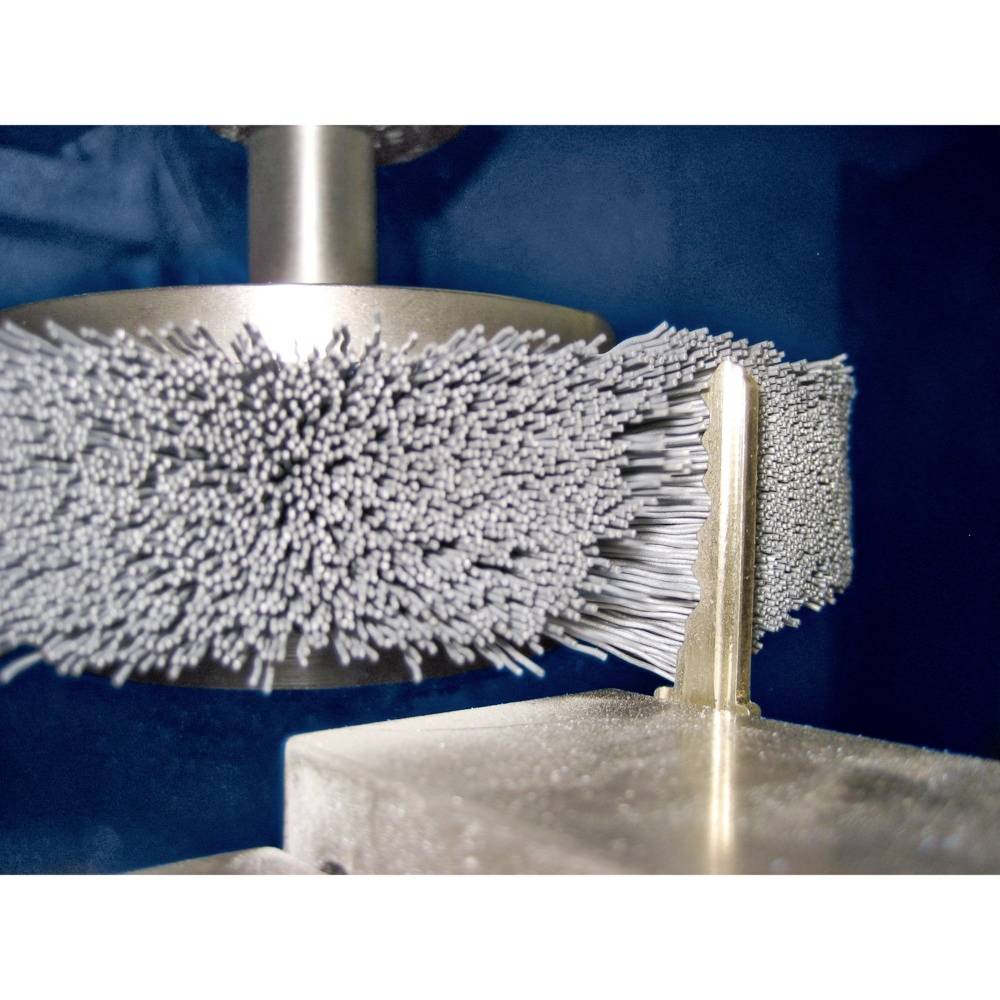 Metallbürstenmaschine bearbeitet dünnen Metallstreifen. Nahaufnahme zeigt rotierende Drahtbürste, die Metalloberfläche glättet.