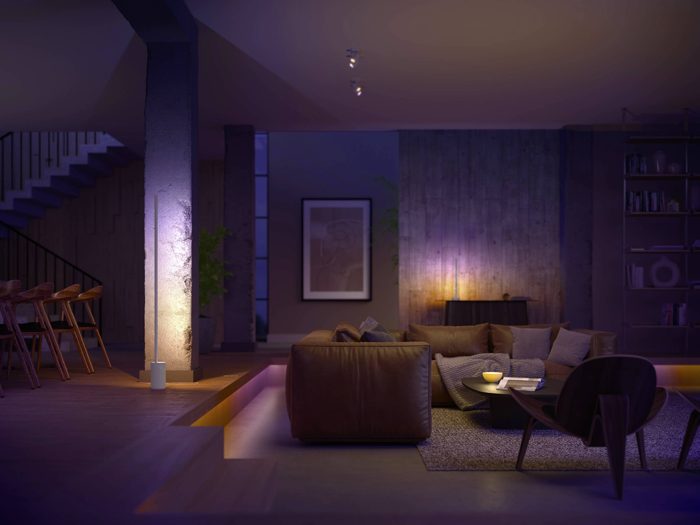 Ein Wohnzimmer mit moderner Beleuchtung. Ein braunes Ledersofa, ein runder Kaffeetisch und ein Regal im Hintergrund. Gedimmtes, warmes Licht.