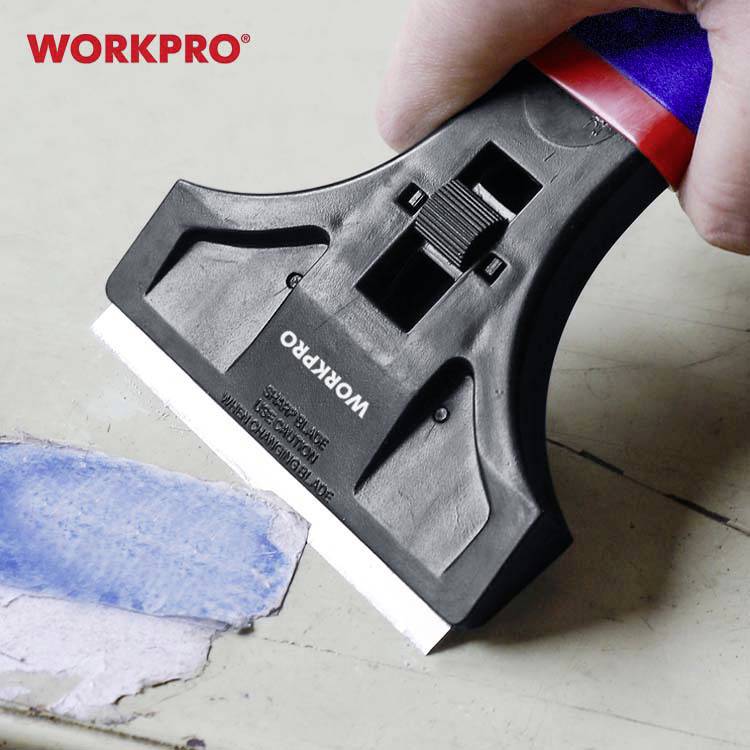 Hand hält Werkzeug mit Klinge, entfernt blaue Farbe von Oberfläche. Oben links rotes 'WORKPRO'-Logo.