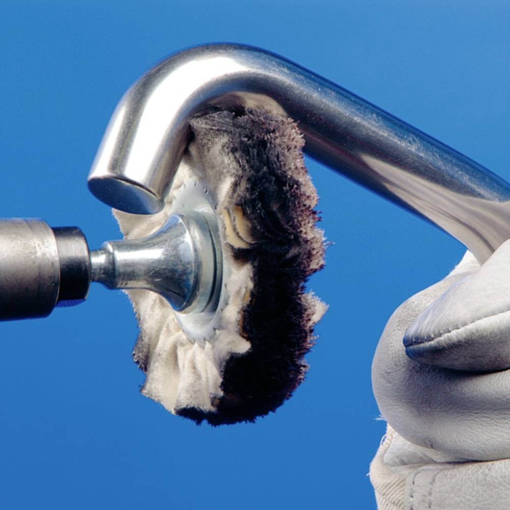 Nahaufnahme eines Metallpolierers, der eine weiche Polierscheibe benutzt, um eine Metalloberfläche zu glänzen. Eine Hand hält das Werkzeug.