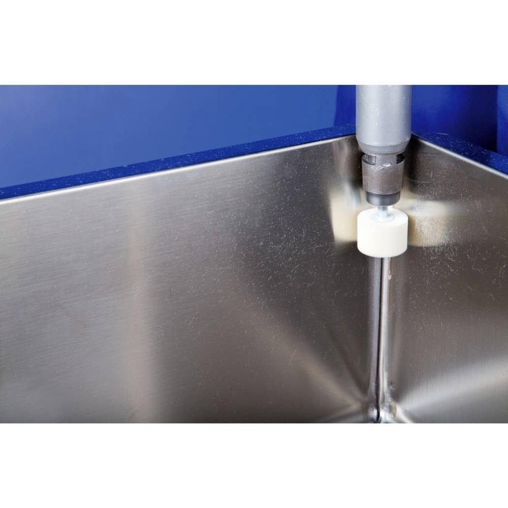 Nahaufnahme einer Wasserstrahldüse in einem Edelstahlbecken. Die Düse spritzt Wasser auf die Metalloberfläche.