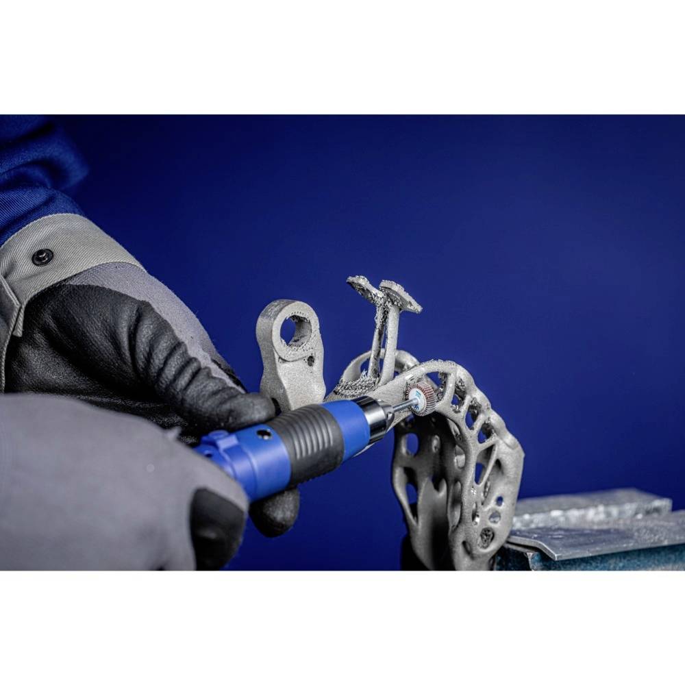 Eine Person bearbeitet mit einem blauen Werkzeug ein Metallteil, möglicherweise für eine Bremsscheibe, vor einem blauen Hintergrund.