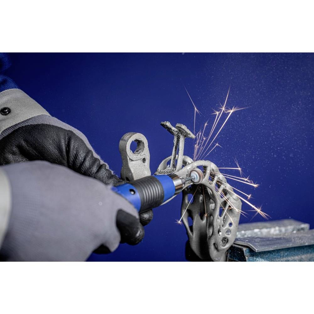 Eine Person schleift ein metallisches Werkstück, Funken fliegen. Die Umgebung deutet auf eine Werkstatt hin.