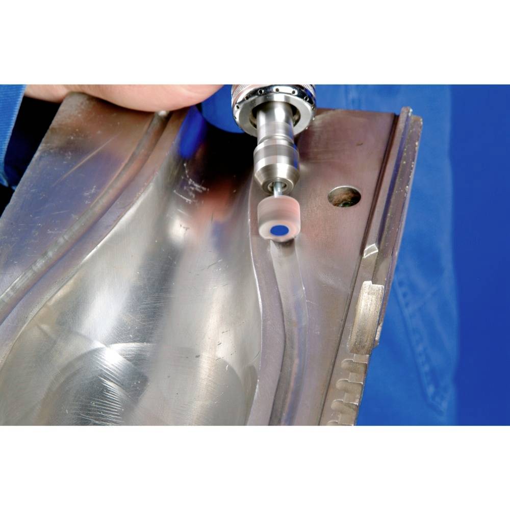 Eine Person poliert eine Metallform mit einem rotierenden Schleifwerkzeug, um die Oberfläche zu glätten und für die Weiterverarbeitung vorzubereiten.