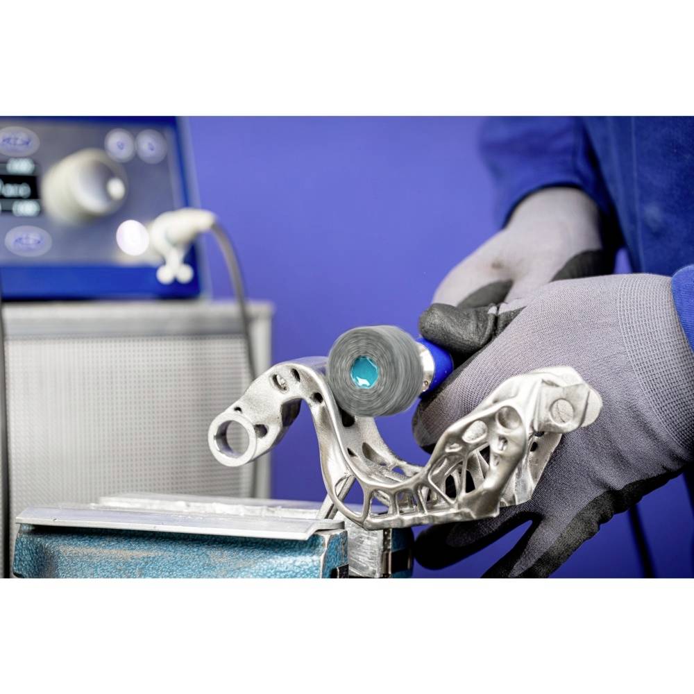 Nahaufnahme eines Objekts aus Metall in einem Labor. Eine Person in Handschuhen hält es in der Hand. Im Hintergrund Laborgeräte.