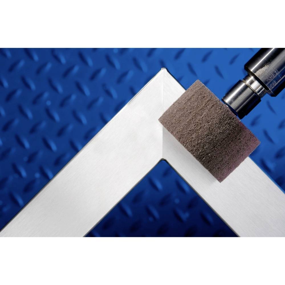 Eine Metallecke wird mit einem Schleifwerkzeug bearbeitet. Der blaue Hintergrund kontrastiert mit dem silbernen Metall.